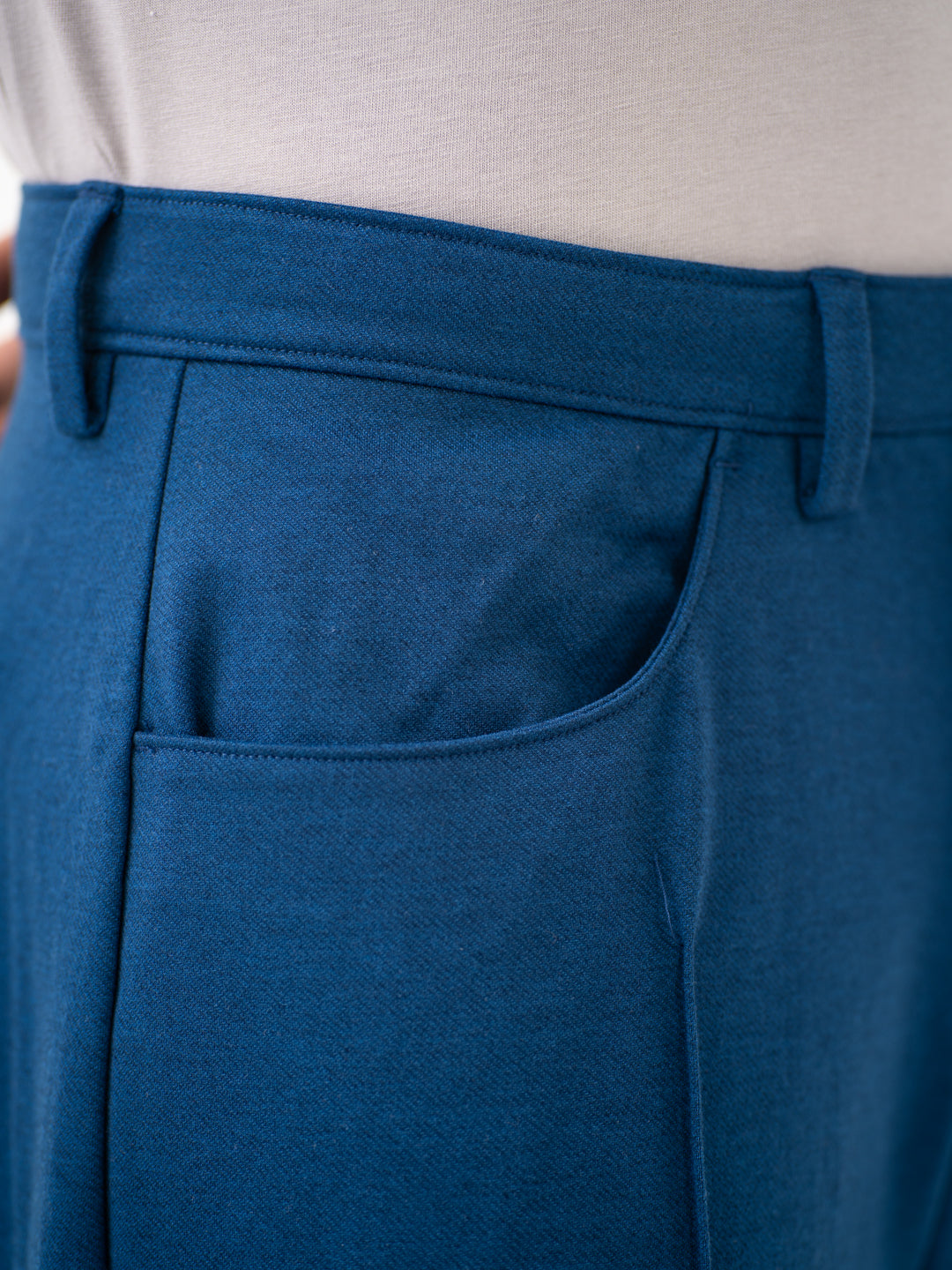 Close-up view of blue pintuck pants by pant project, focusing on the waistband and pocket details