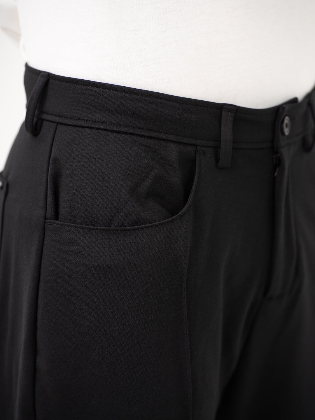 Close-up view of black pintuck pants by pant project, focusing on the waistband and pocket details