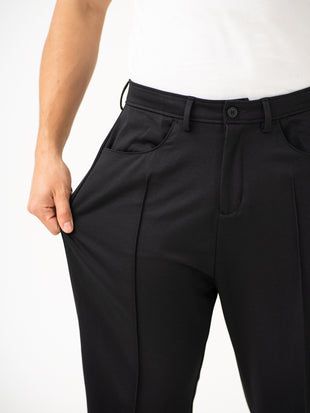Close-up view of black pintuck pants by pant project, focusing on the stretchable waistband and pocket detail