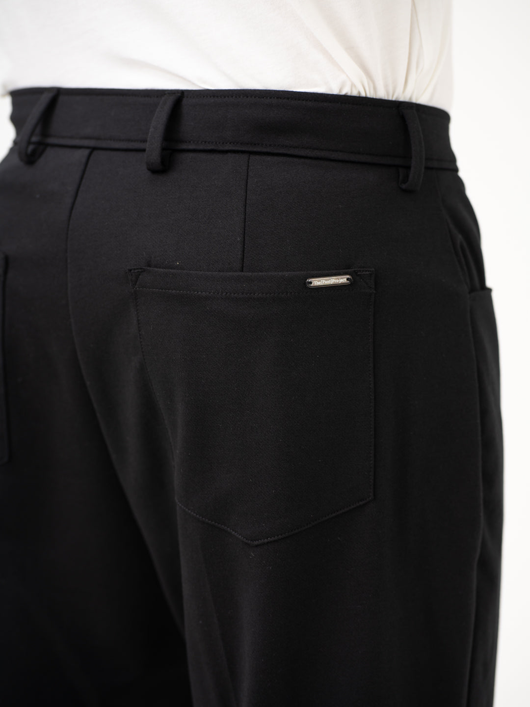 Close-up view of black pintuck pants by pant project, focusing on the back pocket detail