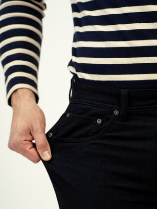 close up view of black jeans by pant project with striped shirt