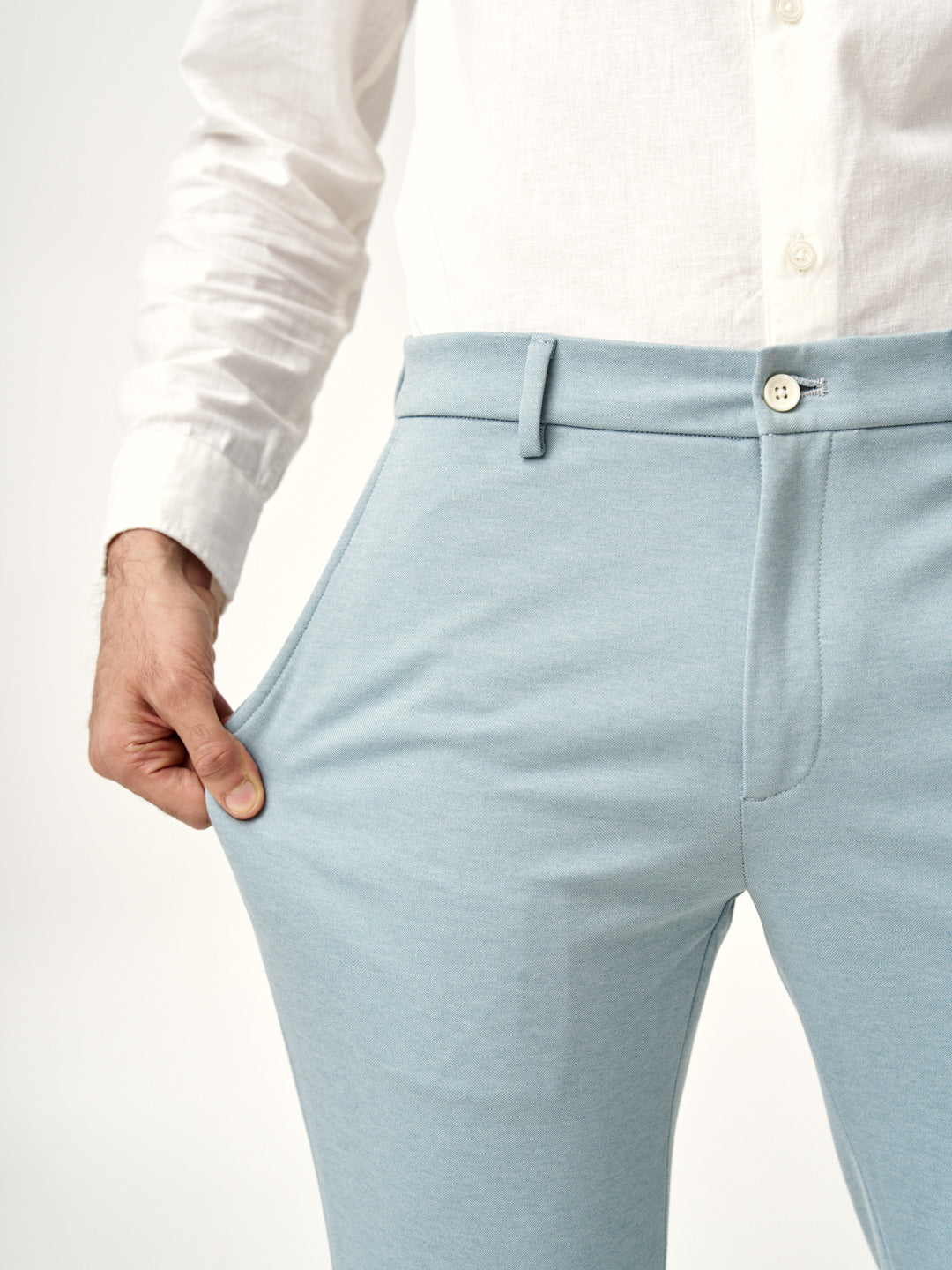 hand stretching the fabric of go blue pants from the Pant Project to show elasticity