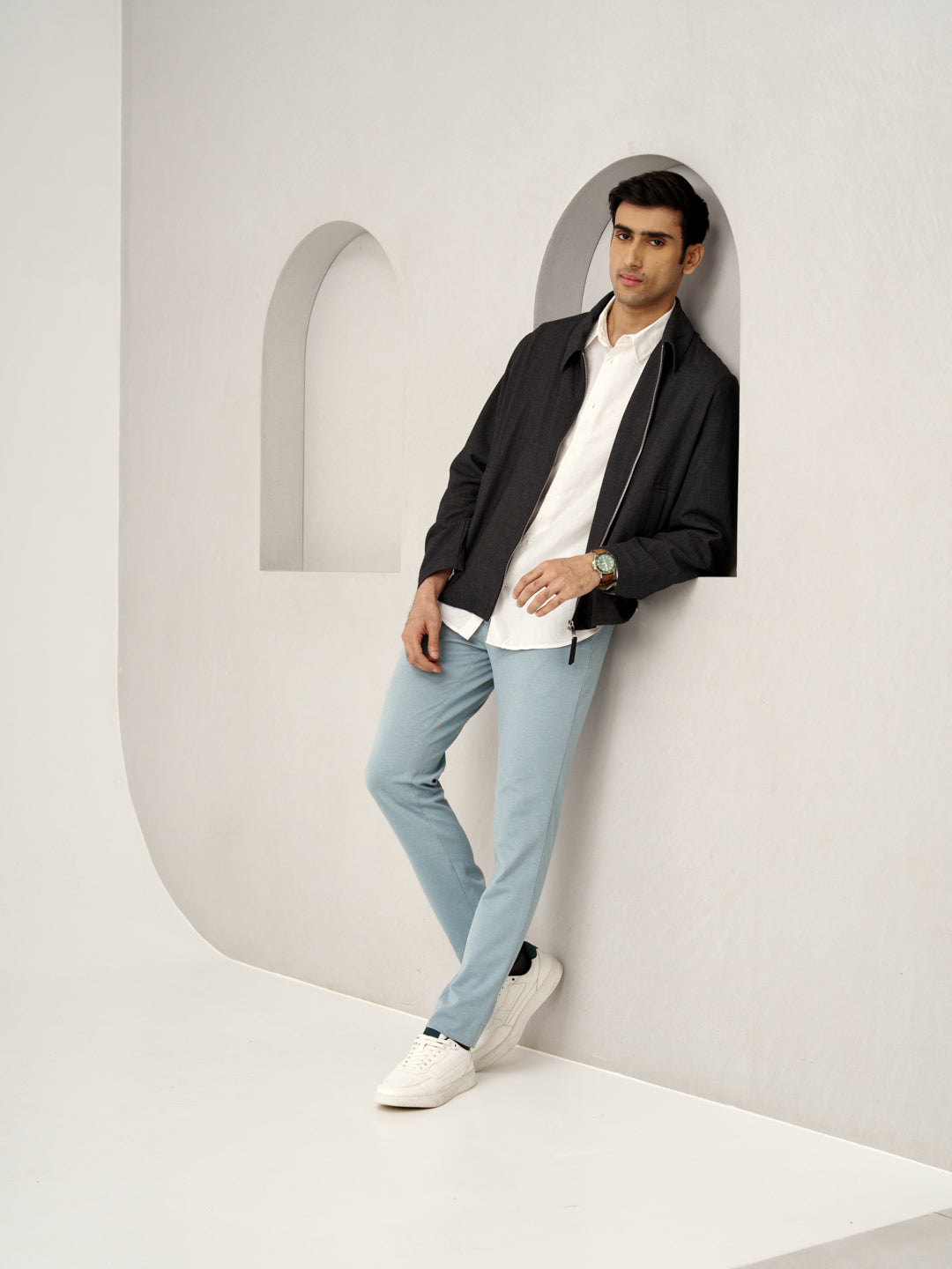 man leaning against the wall in light blue go blue pants from the Pant Project