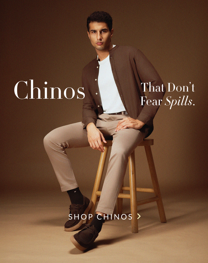 Banner showcasing a model in Pant Project's spill resistant grey chinos alongside a stack of folded colorful pants.