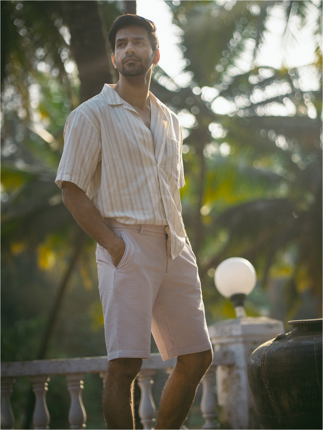 Lifestyle image of pant project's romeo rouge stripes seersucker chino shorts, showcasing red and white stripes in a casual outdoor setting.