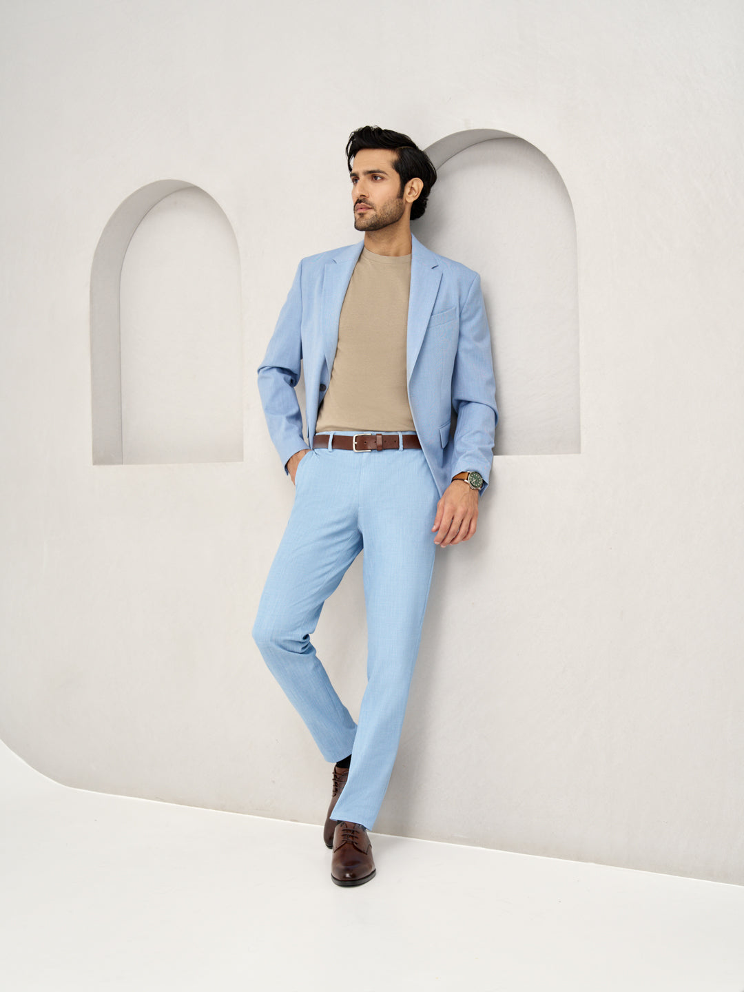 leaning pose showcasing Pant Project's blue bali stretchable trousers