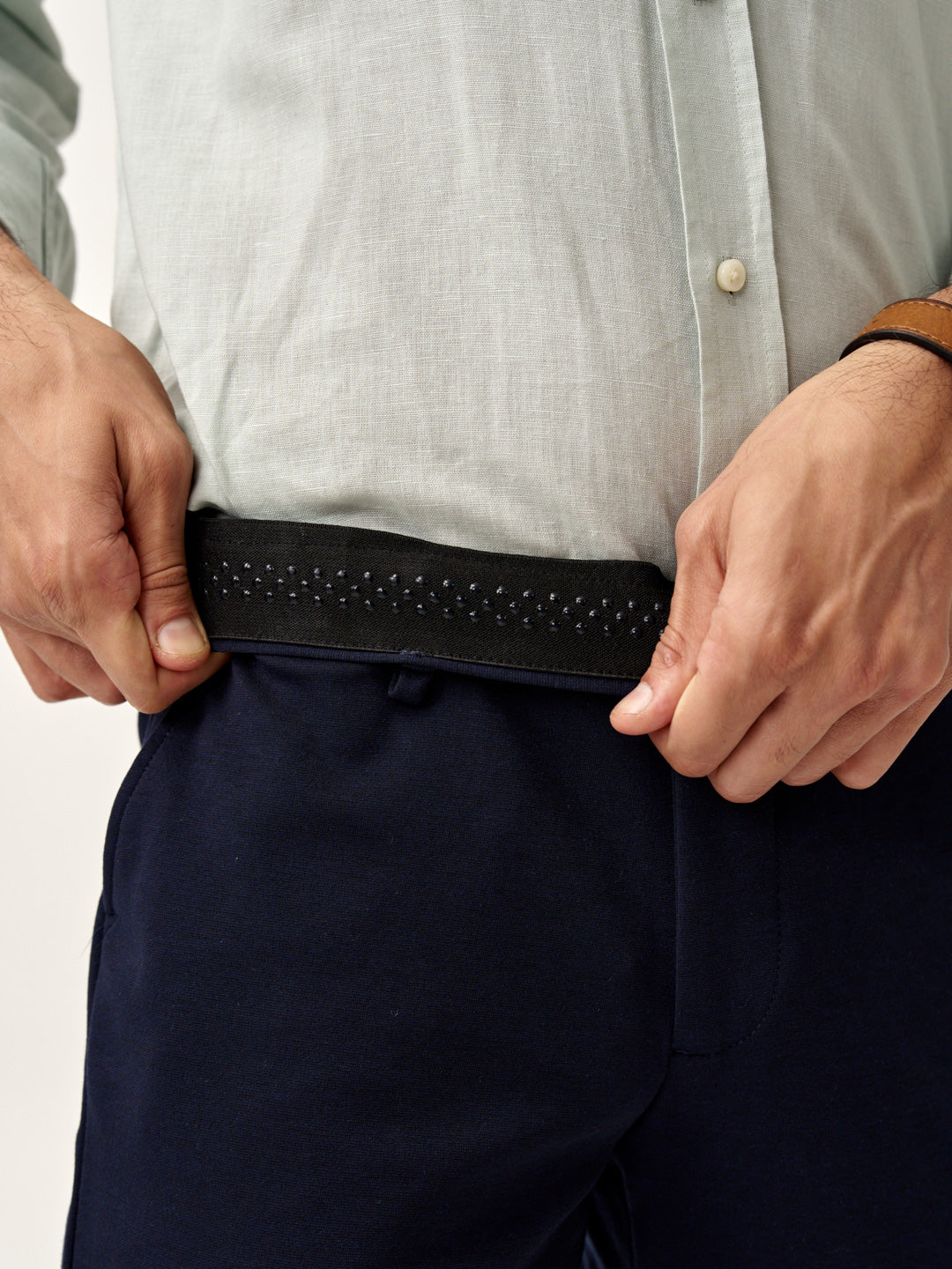 man adjusting waistband of blue check pants from the Pant Project
