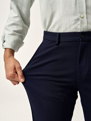 man stretching the fabric of dark navy pants by the Pant Project to show flexibility