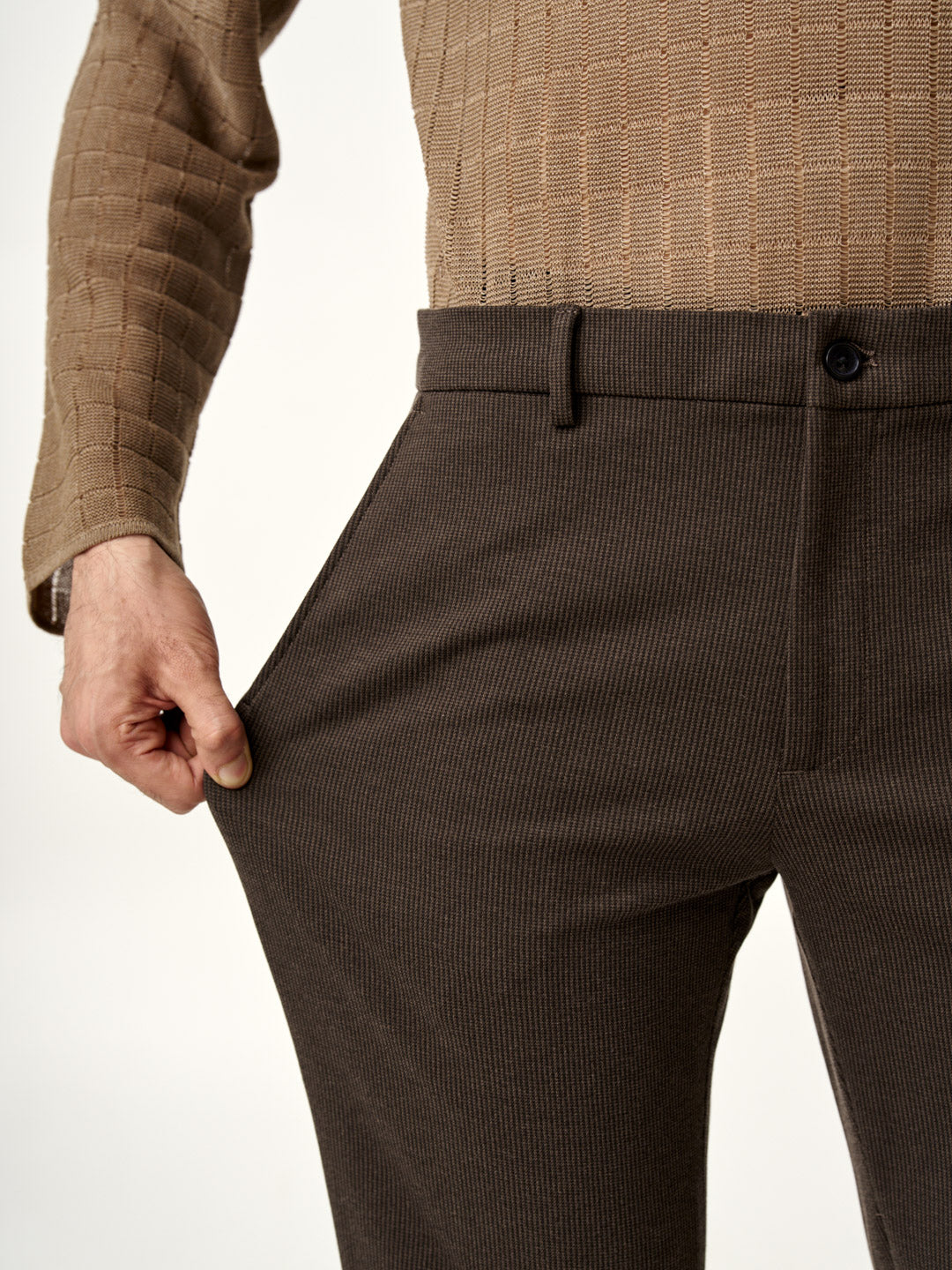 man stretching walnut brown pants by the Pant Project to show fabric flexibility