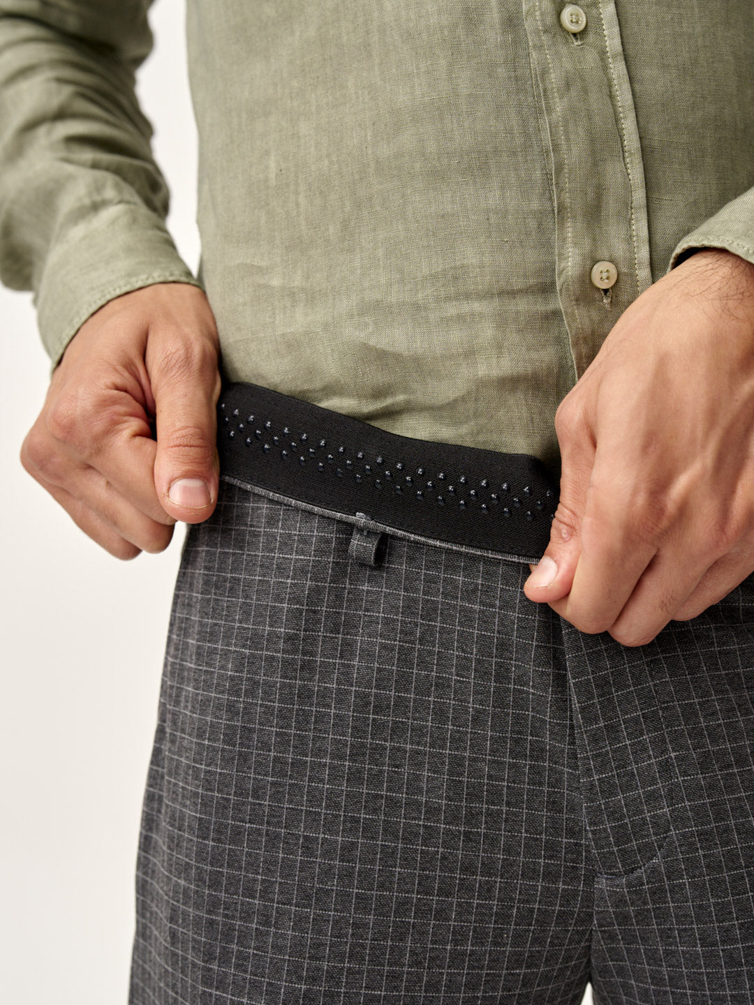 model demonstrates the comfortable waistband of grey check pants by the Pant Project