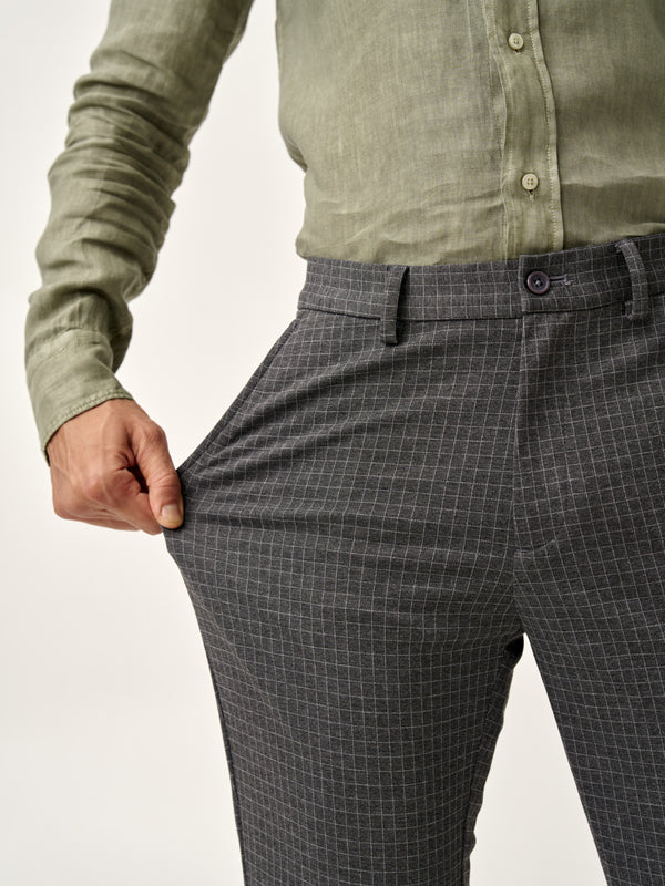model shows the stretchable fabric of grey check pants by the Pant Project